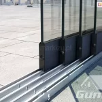 Eine Aluminiumrinne mit vier Führungsschienen und vier verschiebbaren Glaspaneelen für die Terrasse.